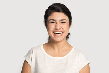 Profile picture of overjoyed millennial Indian female isolated on grey studio background laugh at...