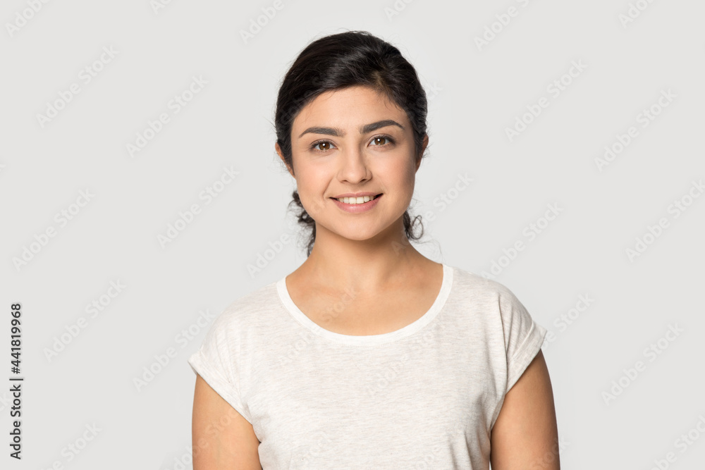 Wall mural profile picture of smiling millennial indian woman isolated on gray studio wall background feeling c