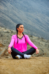 Fototapeta na wymiar mature woman meditating on the mountain in sportswear