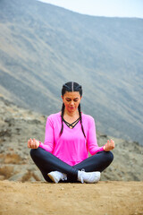 Fototapeta na wymiar mature woman meditating on the mountain in sportswear