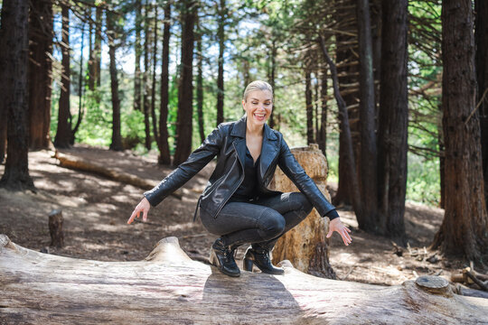 Young Woman Sitting or Standing on Fallen Tree in a Redwood Grove