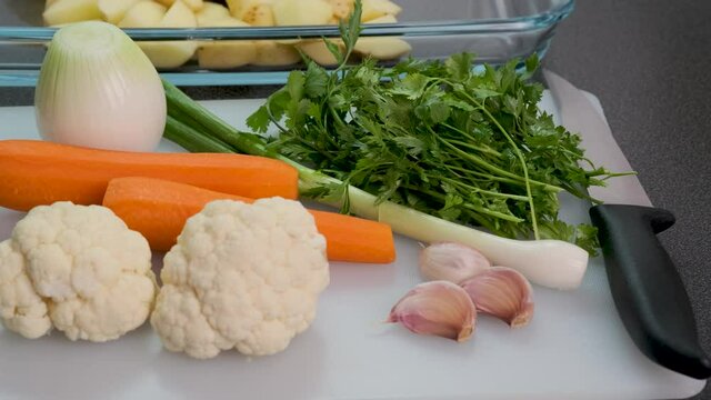 Close up of fresh vegetables on modern kitchen. Potatoes, carrot, onion, garlic on cutting board. Cooking fresh vegetables, ingredients for healthy vegetarian soup, diner, garnish.