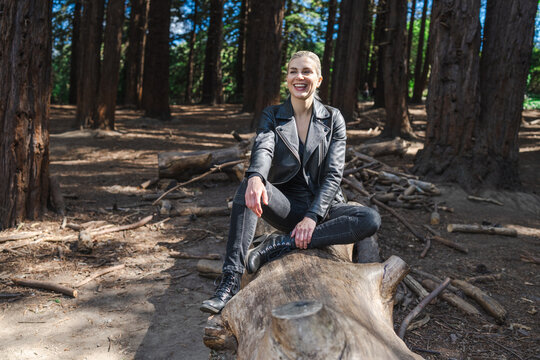 Young Woman Sitting or Standing on Fallen Tree in a Redwood Grove