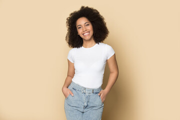 Portrait of smiling young African American woman isolated on yellow studio background wear casual clothes feel optimistic. Happy millennial biracial female show fashion style. Diversity concept.