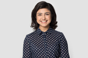 Headshot portrait of smiling Indian young woman isolated on gray studio background look at camera smiling. Profile picture of happy millennial female feel positive optimistic. Employment, hr concept. - Powered by Adobe