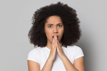Headshot portrait of stunned young African American woman shocked by bad news. Amazed upset millennial mixed race female isolated on grey studio background shook surprised by negative message.