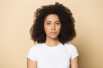 Headshot portrait of serious young African American woman isolated on yellow studio background look at camera. Profile picture of focused millennial biracial female client customer. Diversity concept. - Powered by Adobe