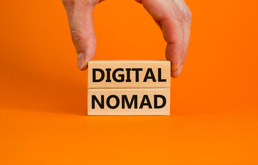 Digital nomad symbol. Wooden blocks with words Digital nomad on beautiful orange background, copy space. Businessman hand. Business and digital nomad concept.