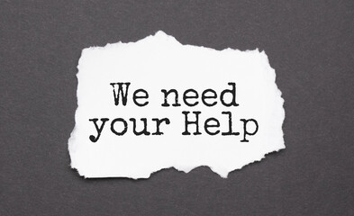 We need your Help sign on the torn paper on the black background