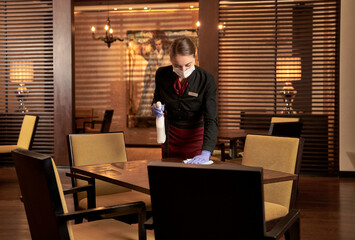 Focused female restaurant employee tidying up a table