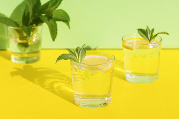 summer drink. cool refreshing beverage with mint and lemon in glass. minimalism. natural fresh lemonade with hard shadows on yellow background
