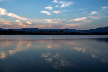 A landscape before sunset. Gently reflected small clouds in the waters of the dam. Kyustendil, Bulgaraia