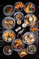 Oktoberfest food, appetizing beer snacks set for big company. mugs of beer and snacks on wooden table, flat lay.