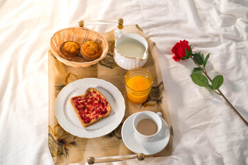 Romantic breakfast in bed with juice, coffee, muffins and toast