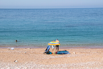 Fototapeta na wymiar Beautiful summer day on the beach, swimming in the blue sea, sunbathing under an umbrella ...