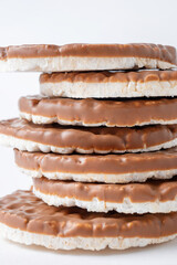 Pile of rice crispbreads coated with chocolate on white background close-up. Crispy puffed round rice bread for healthy diet.