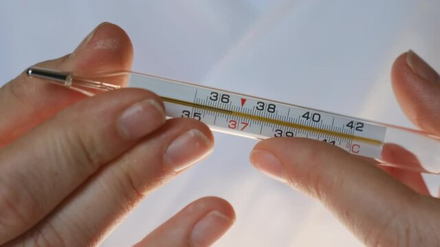 female doctor shows mercury thermometer to camera, on which we see temperature of 36.6 celsius. Person was sick with coronavirus SARS COVID-19 or other disease. Now healthy.