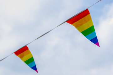Worldwide LGBTQ community concept with pennant rainbow flags waving on the air with blue sky and white clouds background, The symbol of gay, lesbian, bisexual and transgender, LGBT social movements.