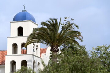 Fototapeta na wymiar Dome and bells of Immaculate Conception Church next to a palm tree