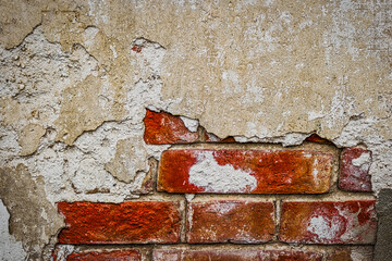 Damaged wall with weathered plaster and old red brickjs. Copyspace. Home renovation or repair works concept