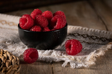 Ripe raspberries in a black ceramic cup