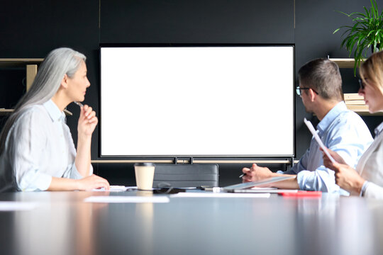 Global corporation online video chat business webinar in meeting room with multiethnic diverse colleagues in office watching big empty blank white screen monitor. Business technologies concept.