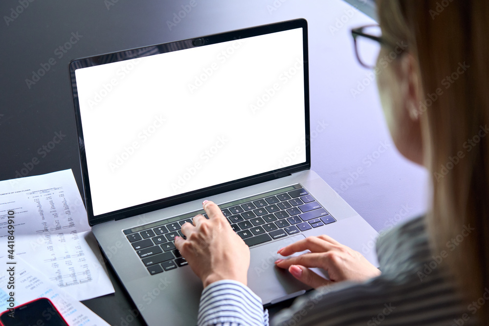 Wall mural Young female ceo executive manager using typing writing email letter using pc laptop computer with empty blank white screen for advertising at desk. Business technologies concept. Over shoulder view.