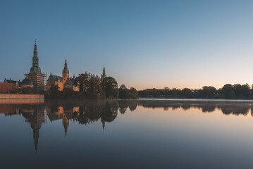 the calm lake of Frederiksborg with reflections of the castle at sunrise