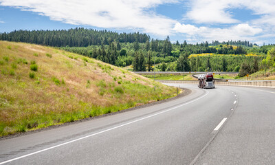 Industrial car hauler big rig semi truck transporting cars on the semi trailer climbing uphill on the interstate highway road