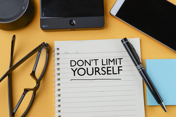 Motivational quote on Dont' Limit Yourself written on the notebook 