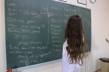 a female student writes on the blackboard in Turkish language course in classroom in one of the...