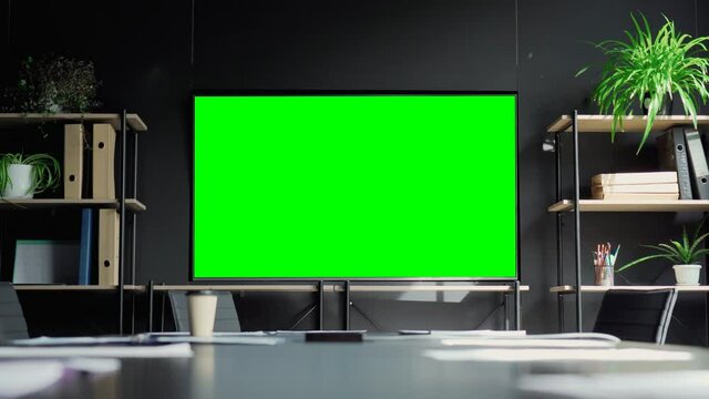 Meeting conference room with blank empty mockup tv screen monitor for advertising standing in modern contemporary office on black wall background. No people. Business technologies concept.