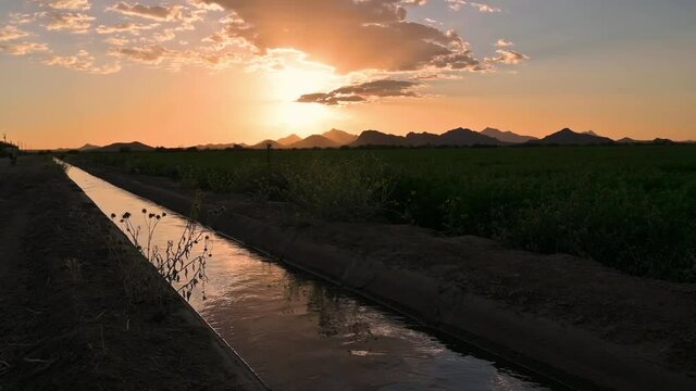 Sunset reflects in water aqueduct used for farming, Tucson Arizona, slow motion