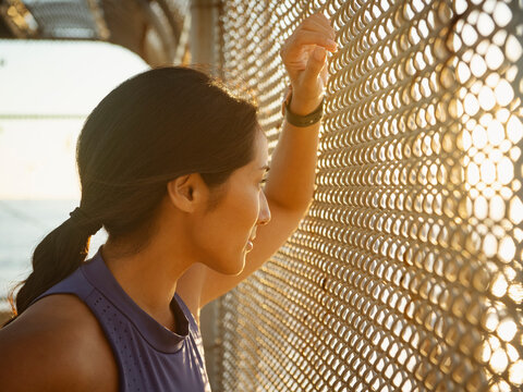 Athlete woman resting at fence - Powered by Adobe