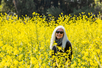 Portrait of smiling senior woman in field of wild mustard