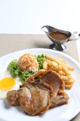grilled golden bbq meat chicken cop pork cutlet beef steak with fried egg, French fries, coleslaw salad and black pepper sauce in pot western cuisine menu
