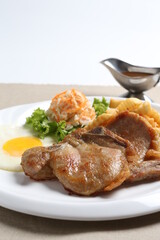 grilled golden bbq meat chicken cop pork cutlet beef steak with fried egg, French fries, coleslaw salad and black pepper sauce in pot western cuisine menu