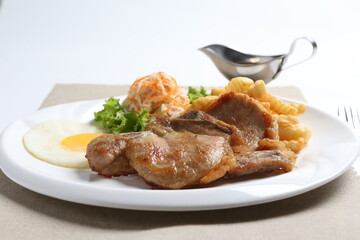 grilled golden bbq meat chicken cop pork cutlet beef steak with fried egg, French fries, coleslaw salad and black pepper sauce in pot western cuisine menu