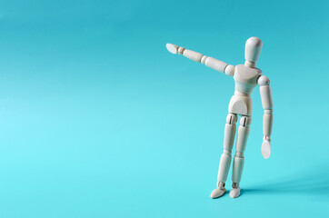The figure of a wooden man pointing with his hand at an empty space. The figure of a wooden man on a colored background kopi space
