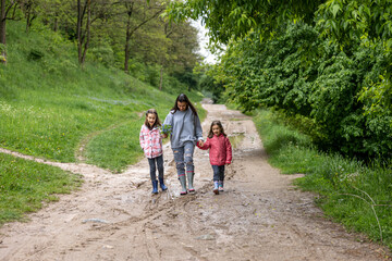 Young mother with daughters on a walk in the forest after the rain.