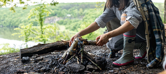 The girl in the forest makes a fire.