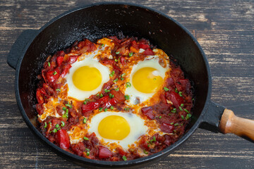 Shakshuka, fried eggs with tomatoes, onion, red pepper and spices in cast iron pan