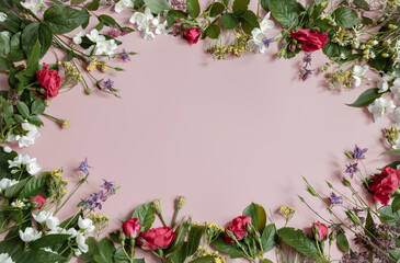 Floral frame of roses and other flowers on a pink background.
