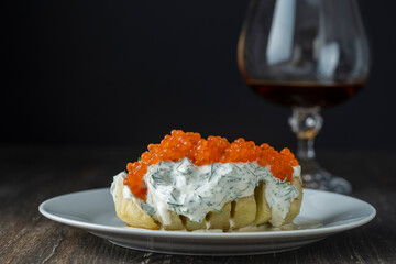 Baked potato with creamy cheese sauce flavoured with dill and red salmon caviar