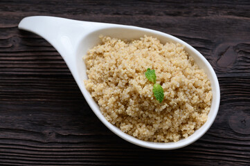 Bowl of boiled quinoa on wood background