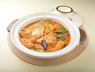 chef cook home style nyonya spicy curry grouper fish head with vegetables in big clay pot