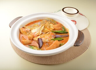 chef cook home style nyonya spicy curry grouper fish head with vegetables in big clay pot