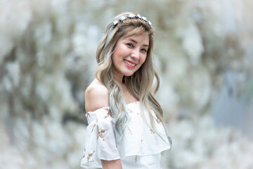 Romantic portrait of beautiful woman in fluttering white dress standing in the white flower with warmest winter