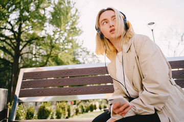 Blonde sitting on a bench with mobile phone