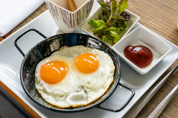 Breakfast - Sunny side up fried eggs with tomato sauce and potato wedges.